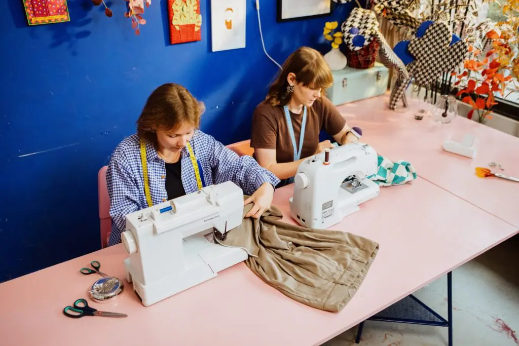 Twee personen aan het werk achter de naaimachine.