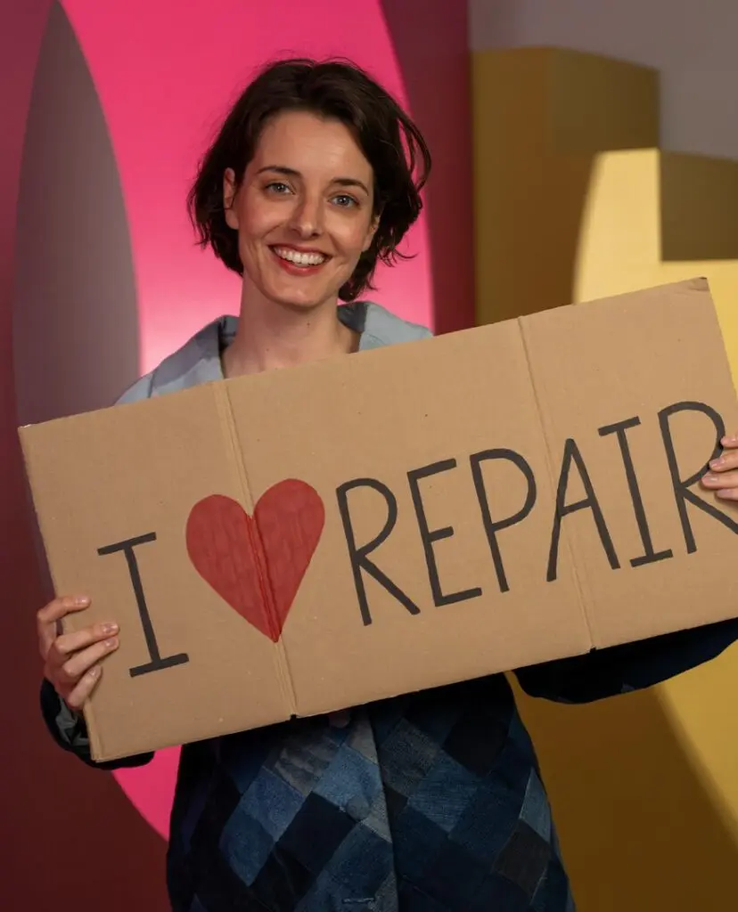 Een vrouw die een kartonnen bordje vasthoudt waarop staat I love repair.