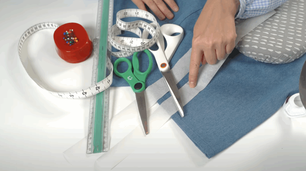 Handen meten en markeren een broek om deze in te korten zonder naaimachine.