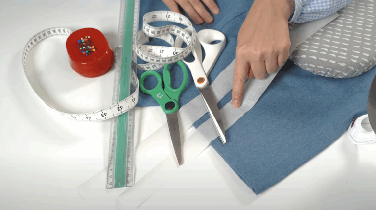 Handen meten en markeren een broek om deze in te korten zonder naaimachine.