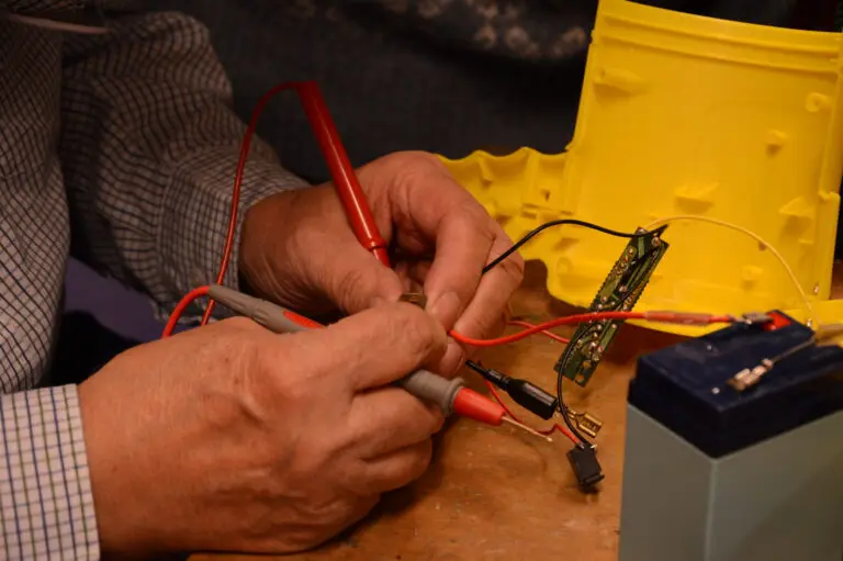 Twee handen die bezig zijn met het repareren van een elektronisch apparaat