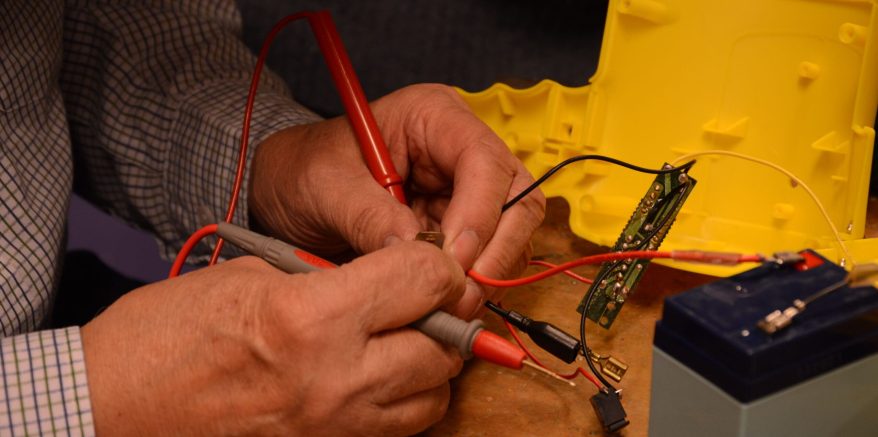 Twee handen die bezig zijn met het repareren van een elektronisch apparaat
